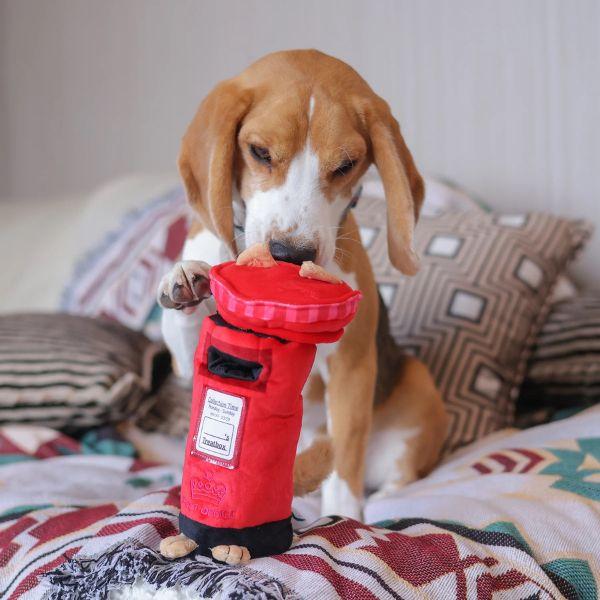 Beagle dog plays with a red plush Woof² British Postbox Treat-Dispensing Dog Toy