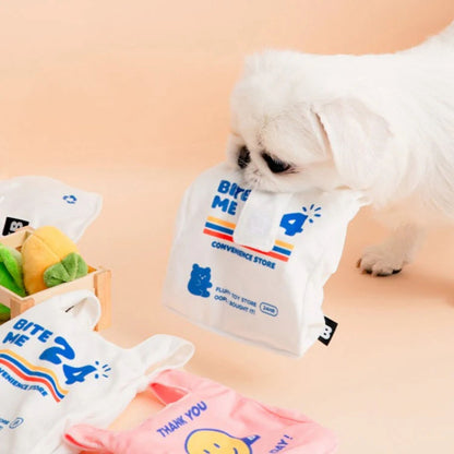 Small white dog carrying the BITE ME Crinkle Bag Nosework Dog Toy during playtime