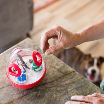 Hand Placing Treats Inside P.L.A.Y. Wobble Ball 2.0 Holiday Edition Red Dog Toy