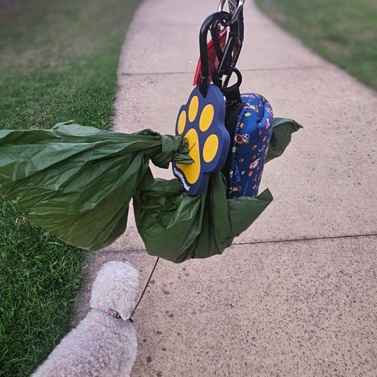 Dog walking with Pawcurement Happy Paw Poop Bag Holder attached to leash, carrying waste bags and accessories