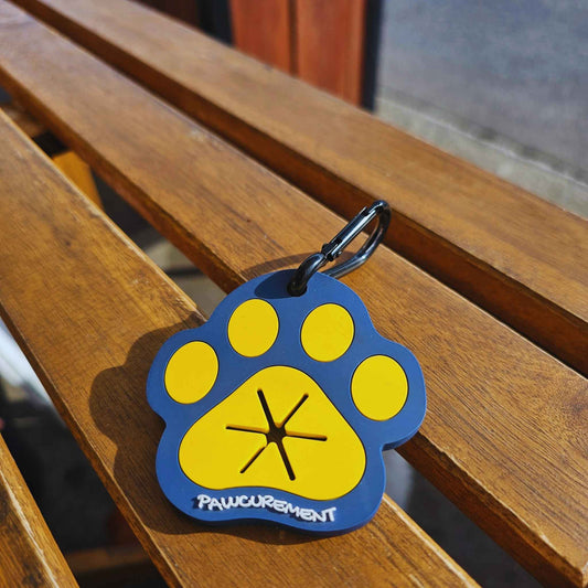 Pawcurement Fetch for Life Poop Bag Carrier with black carabiner clip resting on a wooden bench in natural light