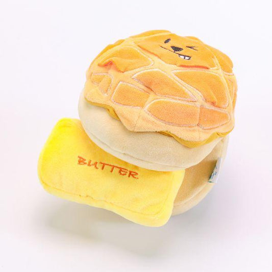 Angled view of the Woof² Buttered Pineapple Bun 2-in-1 Dog Toy showing the plush bun design with removable butter piece.